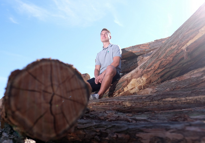 Das Bild zeigt Justin Kollautz von Timbercut auf Baumstämmen sitzend.